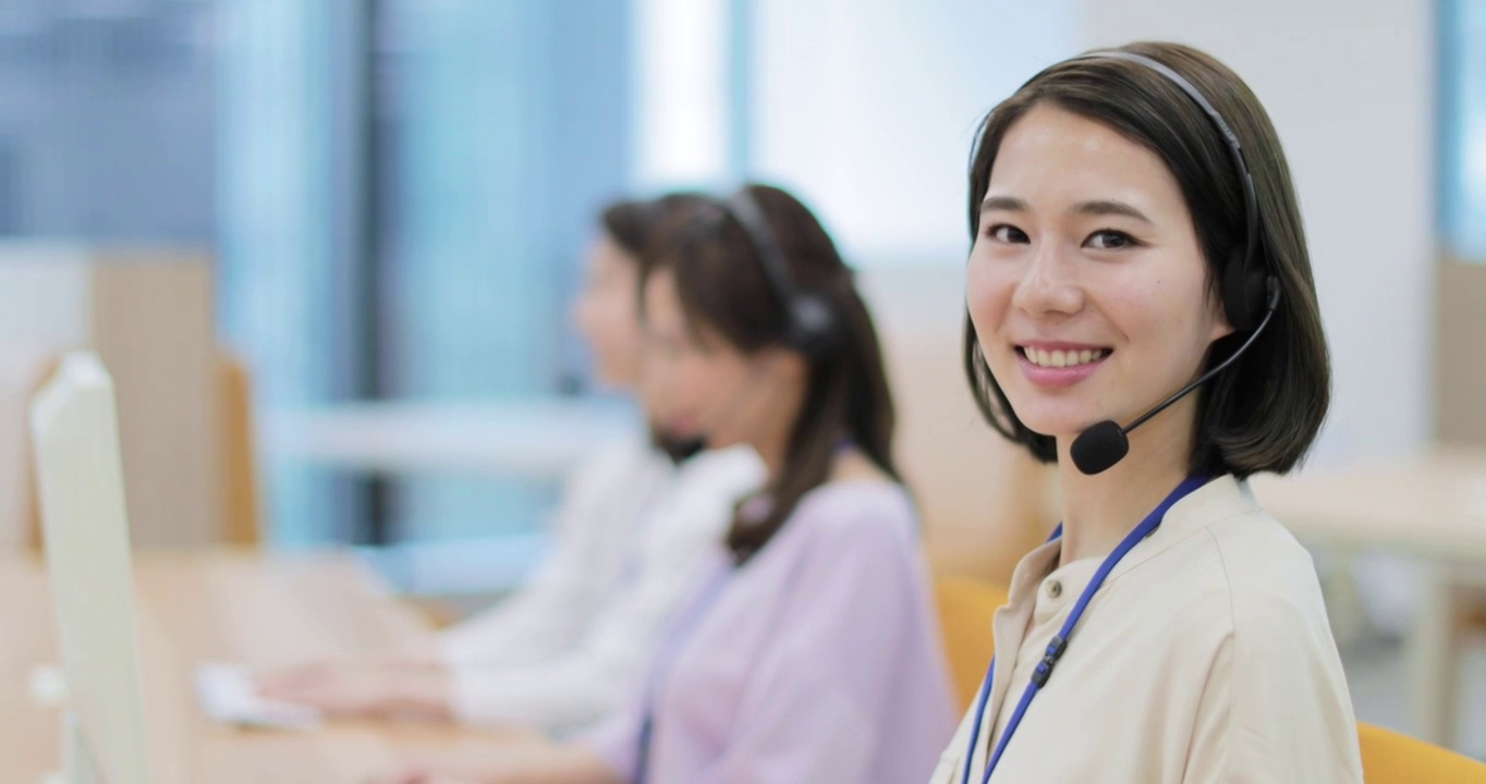 年轻的日本呼叫中心接线员在工作时对着镜头微笑视频下载