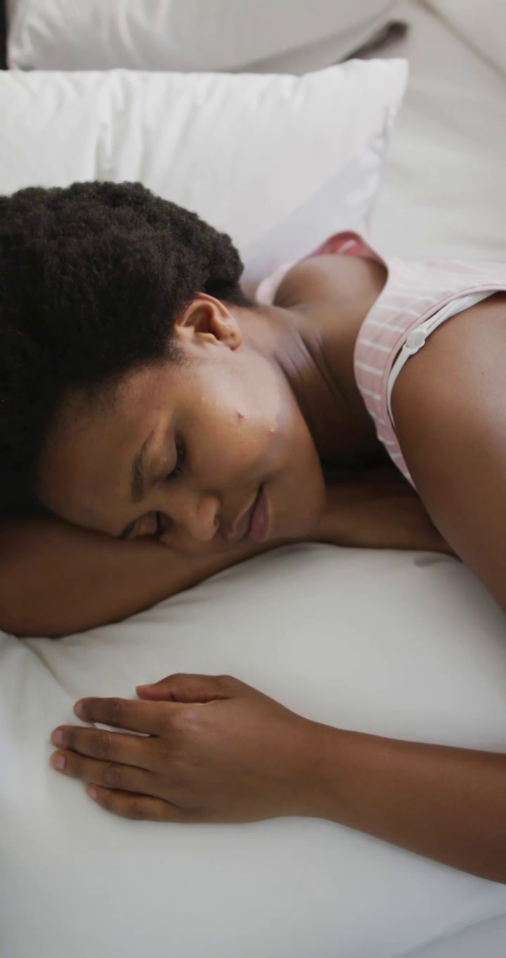 垂直视频快乐的非洲裔美国女人躺在家里的床上视频下载
