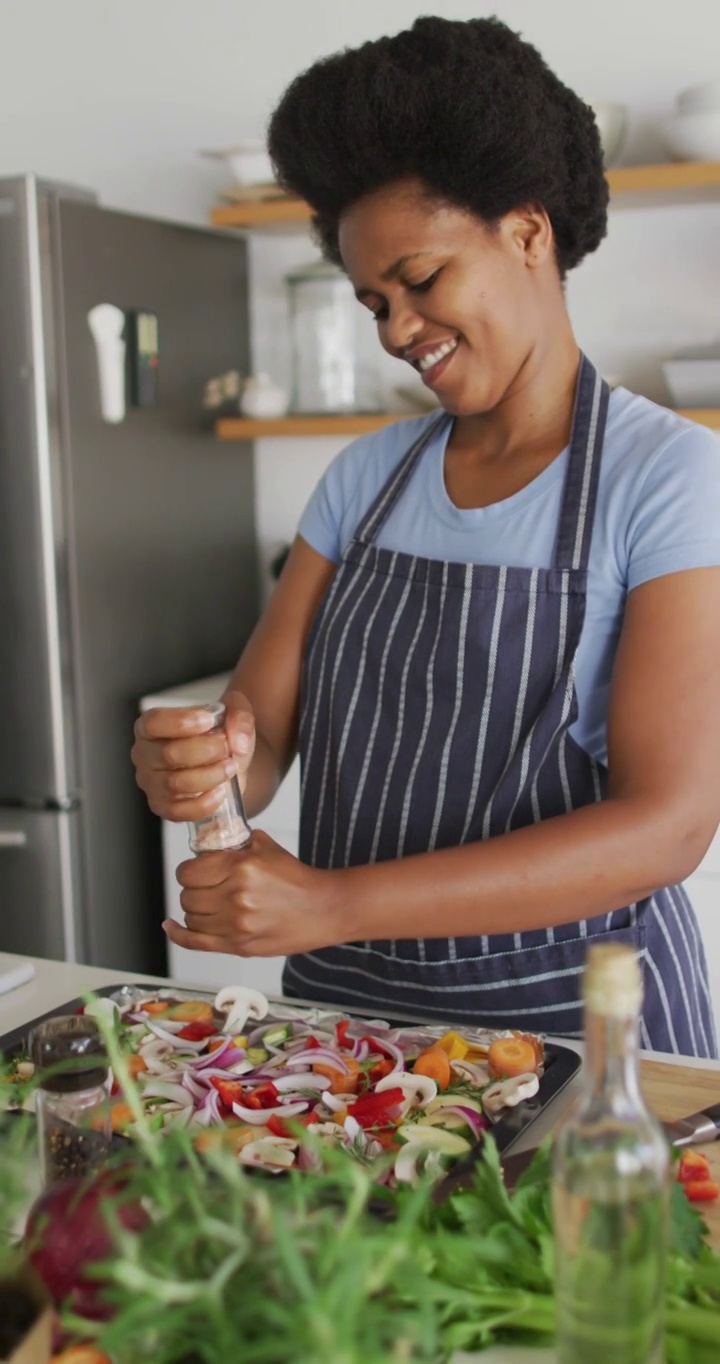 一个快乐的非裔美国女人在家做饭的垂直视频视频下载