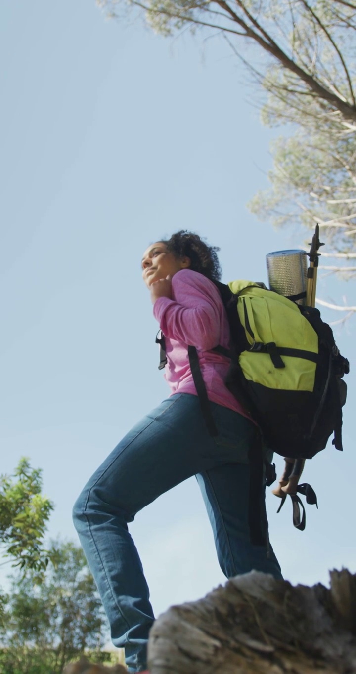 垂直视频快乐的非洲裔美国女人与背包徒步在农村，享受景色视频下载