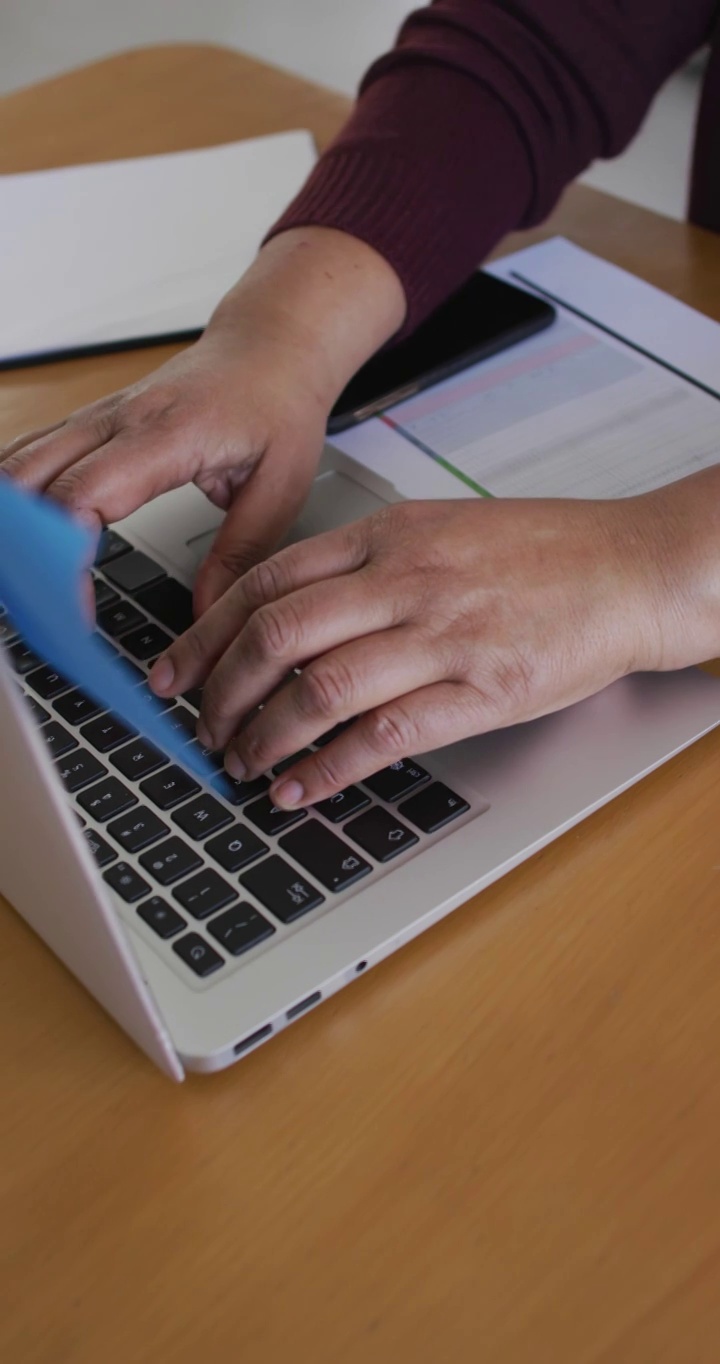 垂直视频的高级非洲裔美国妇女的手在桌子上的笔记本电脑键盘上打字视频下载