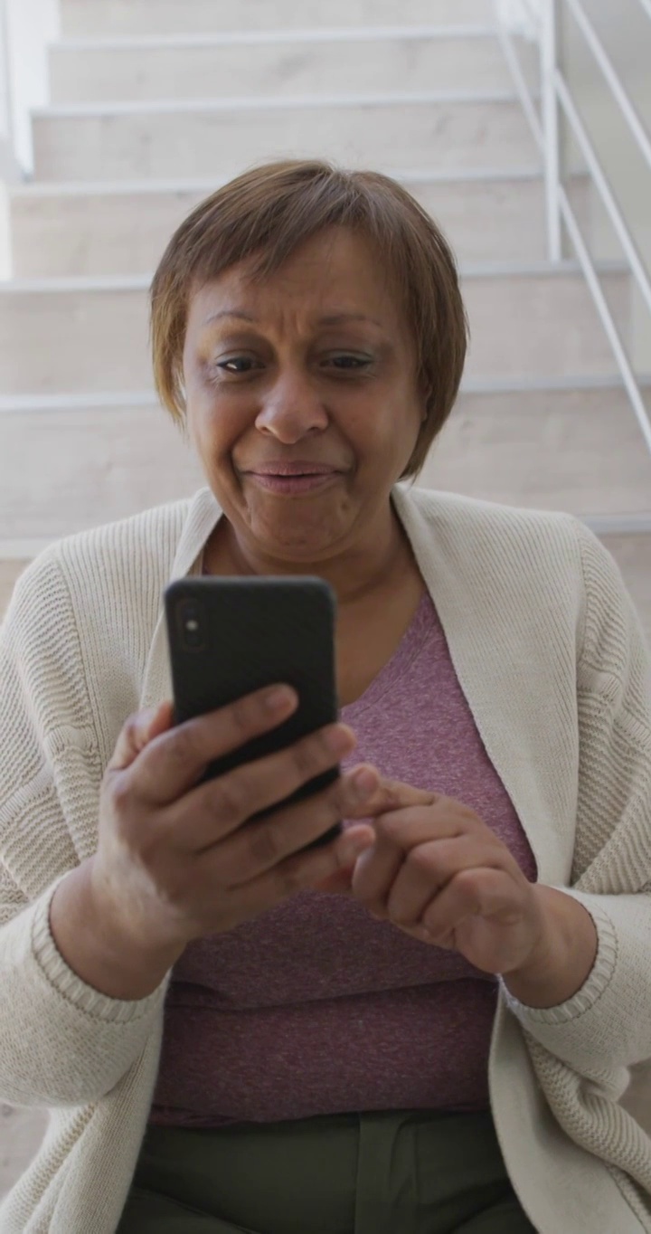 垂直视频快乐的高级非洲裔美国妇女在智能手机上视频通话，挥手视频下载