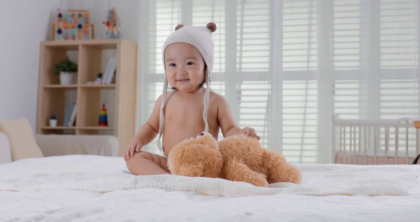 可爱的小宝宝坐在床上玩耍视频下载