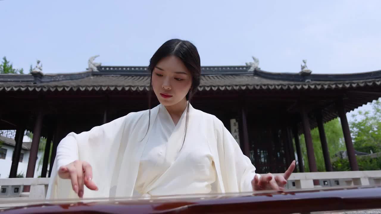 一个汉服美女坐在中式大殿前弹古琴慢动作（选编）视频素材