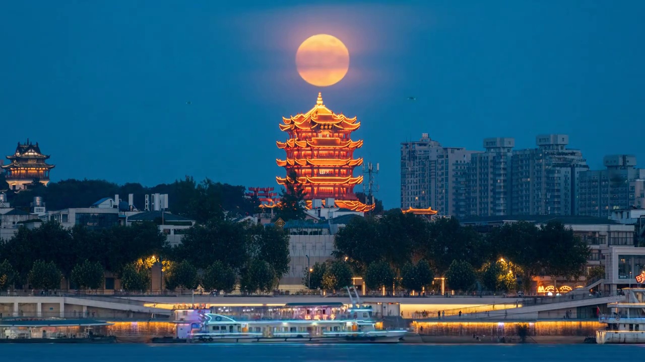 隔江遥望武汉市地标黄鹤楼后的超级月亮升起，长江上各种船只来来往往视频素材