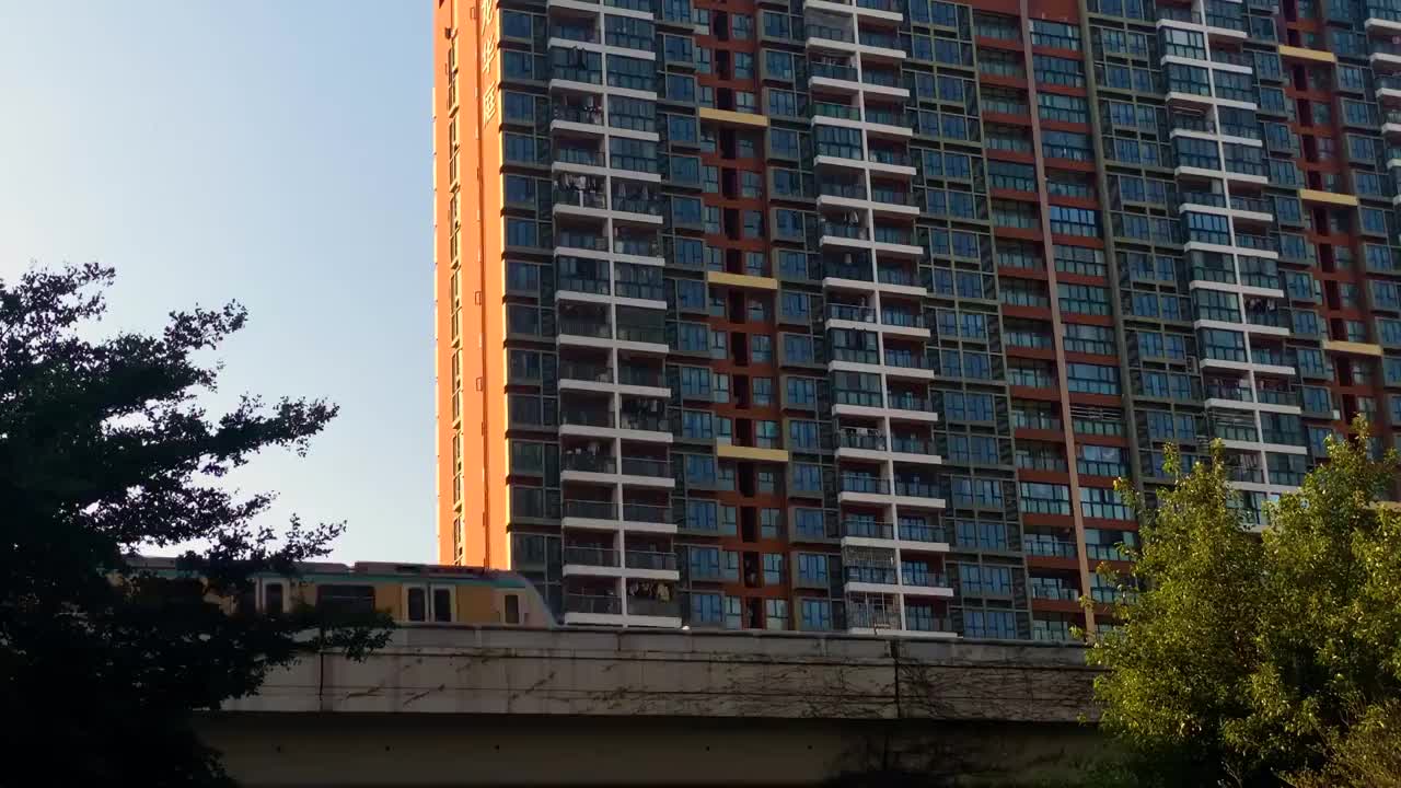 朝阳下运行中的城市地铁运输穿行在城市高楼之间视频素材