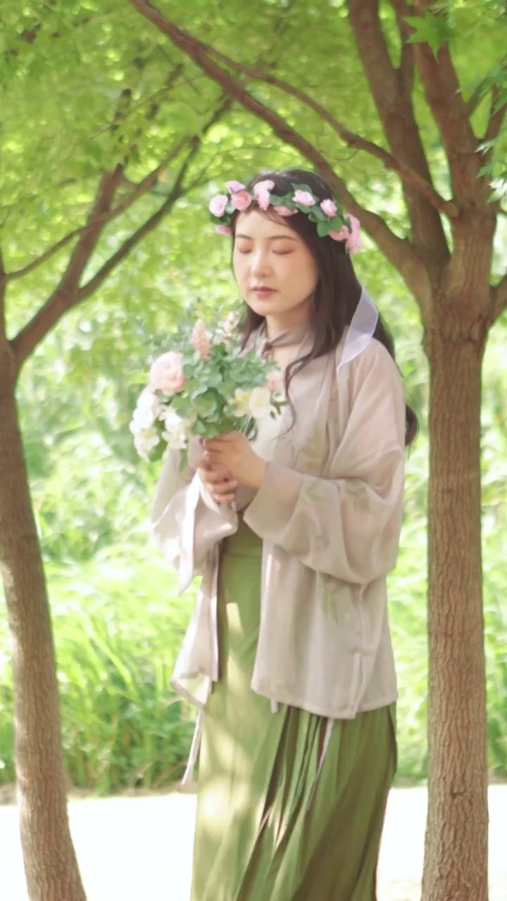 亚洲美女在公园树林里拿着花束走路转圈视频下载