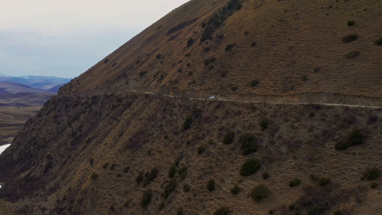 航拍越野车行驶在高原草甸半山腰的土路上视频素材