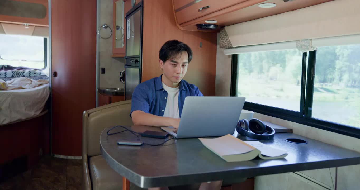 房车内的青年男人使用笔记本电脑视频下载