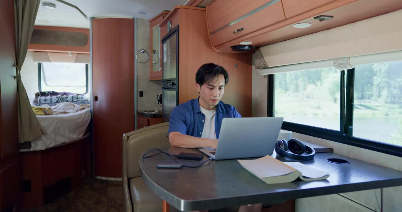 房车内的青年男人使用笔记本电脑视频下载
