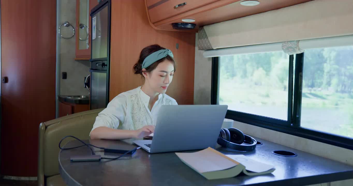 房车内的青年女人使用笔记本电脑视频下载