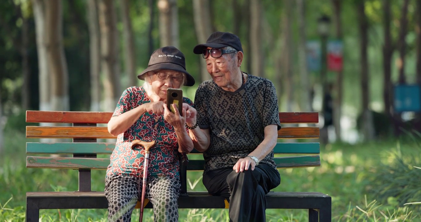 幸福的老年夫妇在公园一起看手机聊天视频下载