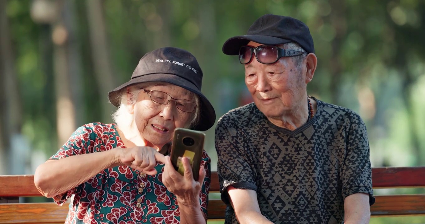 幸福的老年夫妇在公园一起看手机聊天视频下载