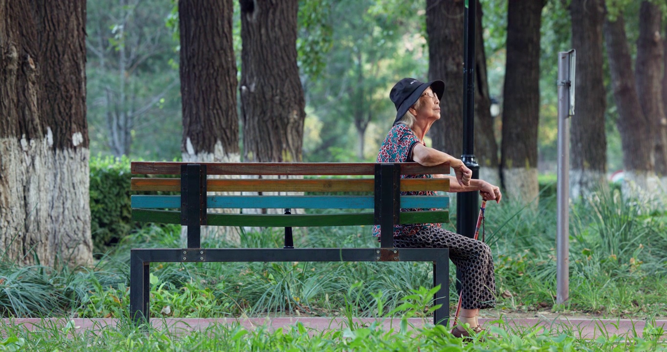 老年人手拄着拐棍孤独的坐在公园长椅上视频素材