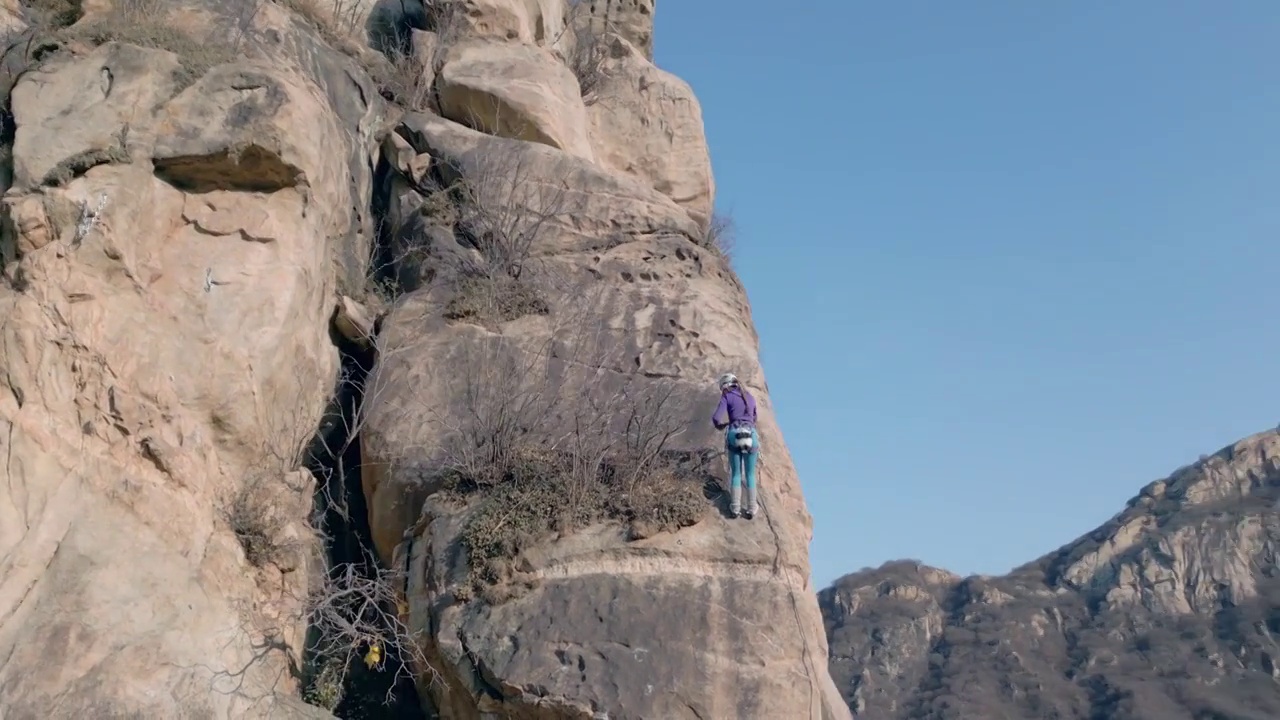 青年女人在悬崖峭壁上攀岩视频下载
