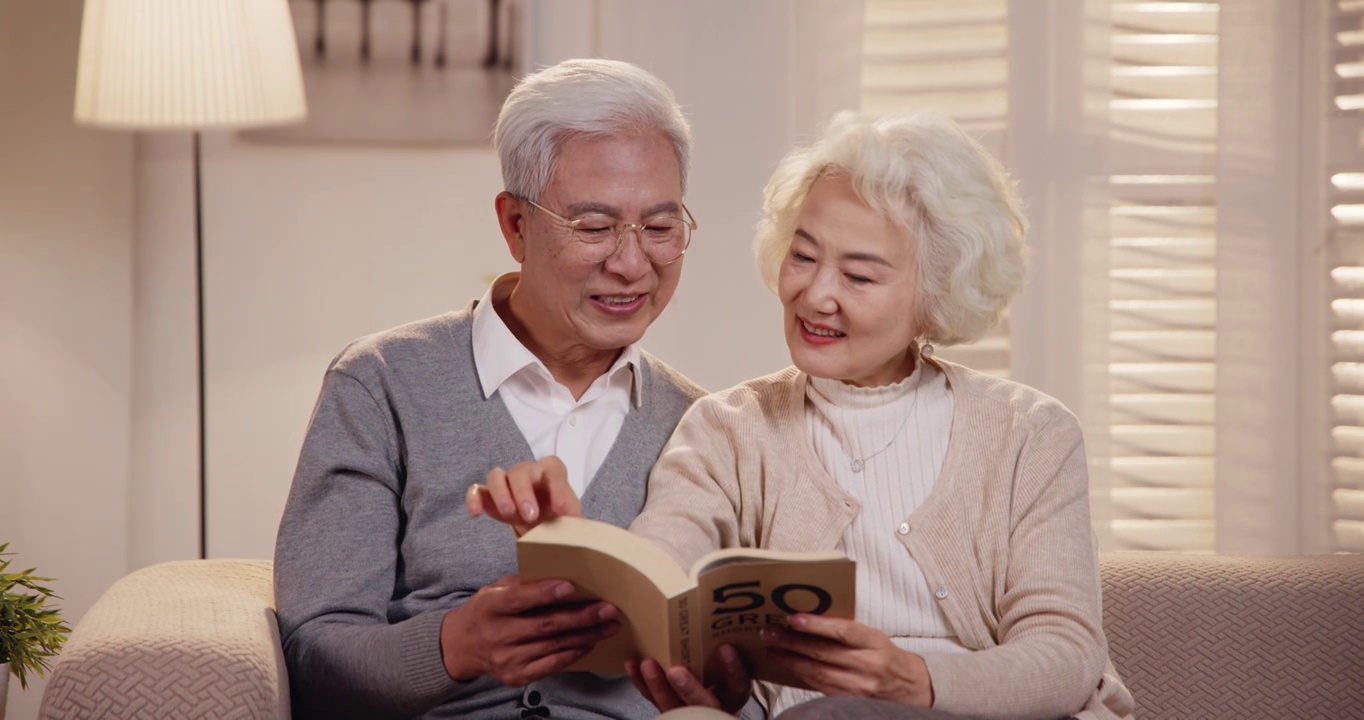 老年夫妇坐在沙发上看书视频素材