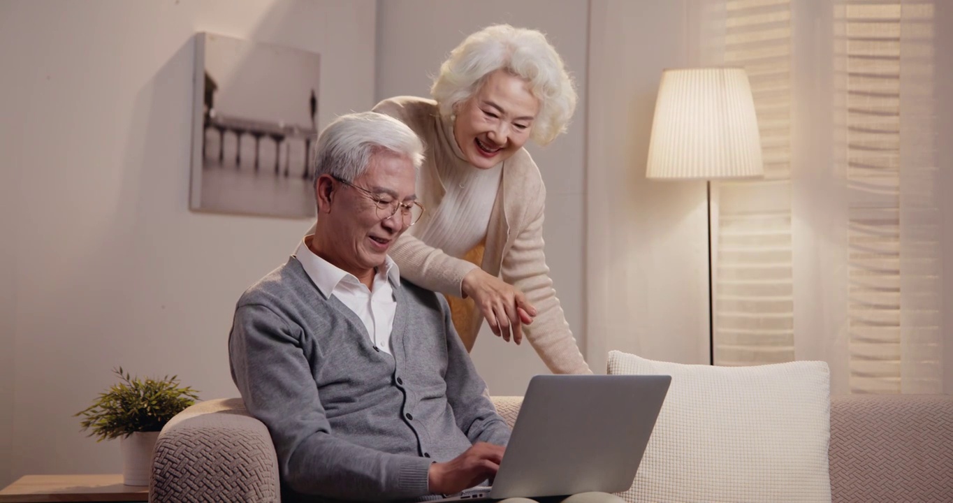 老年夫妇坐在沙发上使用笔记本电脑视频素材