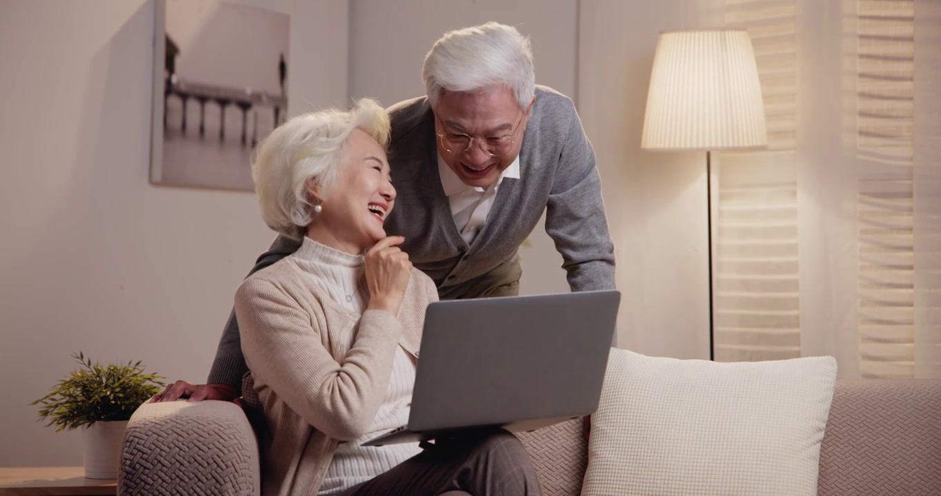 老年夫妇坐在沙发上使用笔记本电脑视频素材