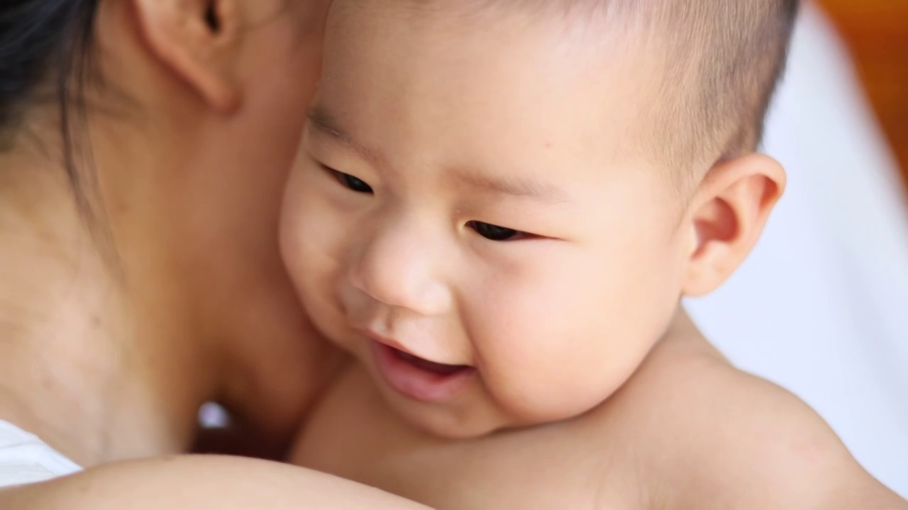 母亲抱着婴儿耳语宝宝开心大笑视频下载
