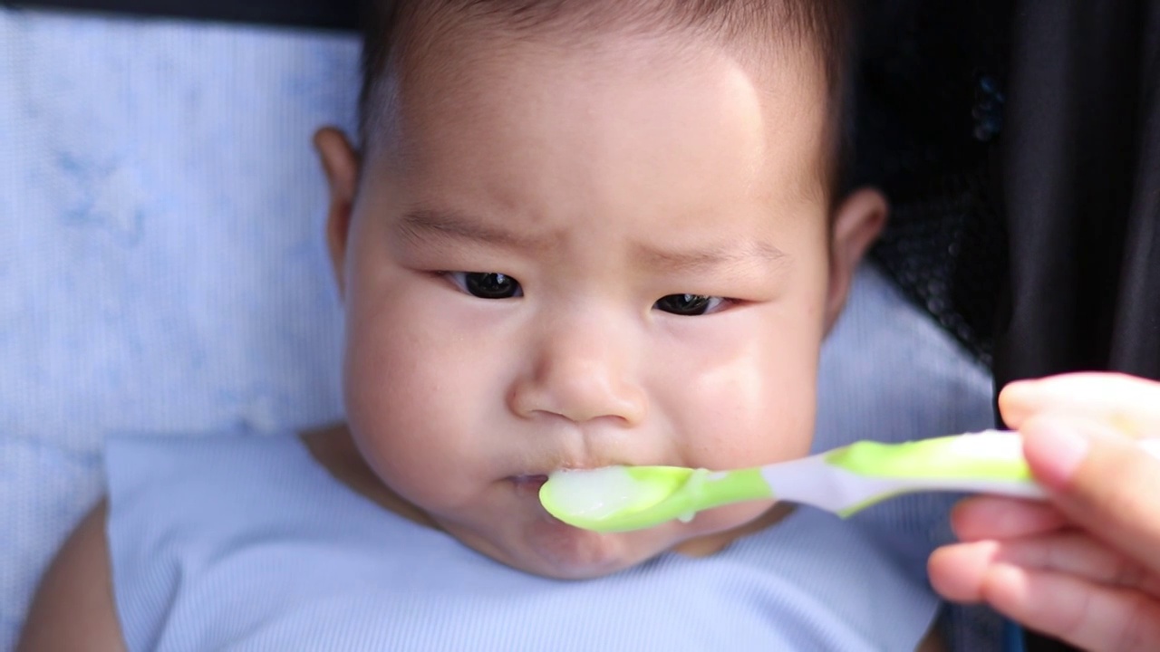 夏季户外婴儿车上喂宝宝吃米糊视频素材