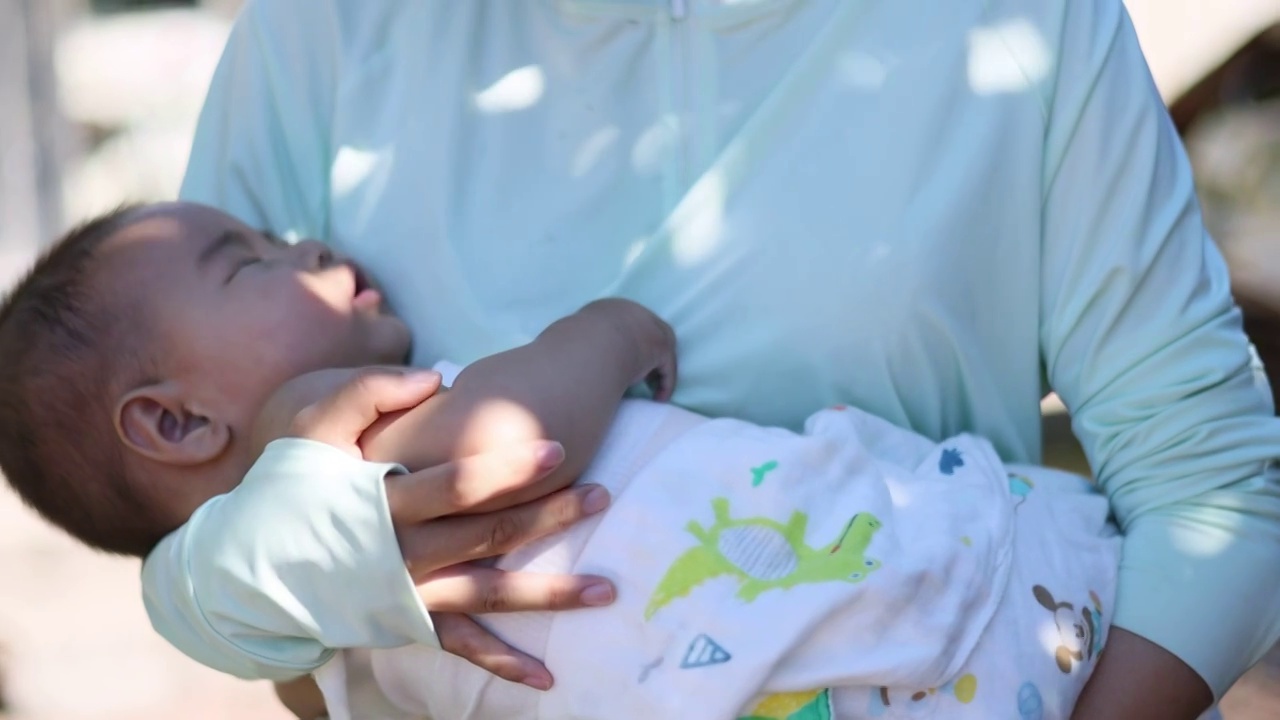 夏季树荫下母亲抱着熟睡的婴儿乘凉视频下载