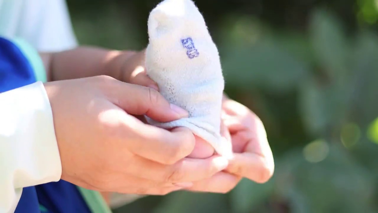 夏季树荫下母亲给赤脚婴儿穿袜子视频下载