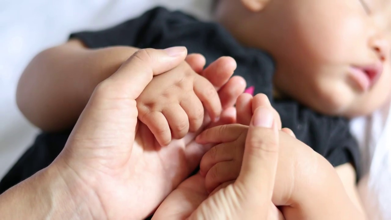 妈妈双手握着睡觉的宝宝的小手按摩视频下载