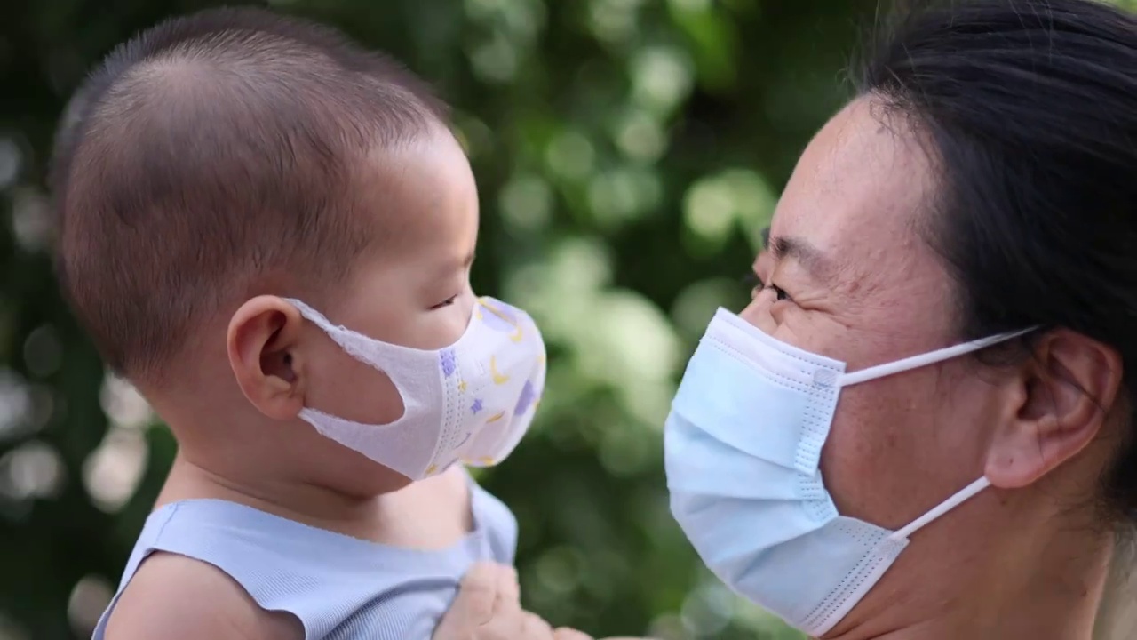 夏季树荫下妈妈和宝宝戴着口罩嬉戏玩耍预防病毒流感视频下载