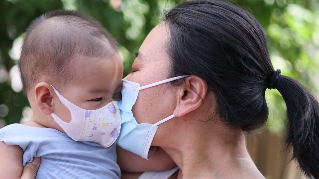 夏季树荫下妈妈和宝宝戴着口罩嬉戏玩耍预防病毒流感视频下载