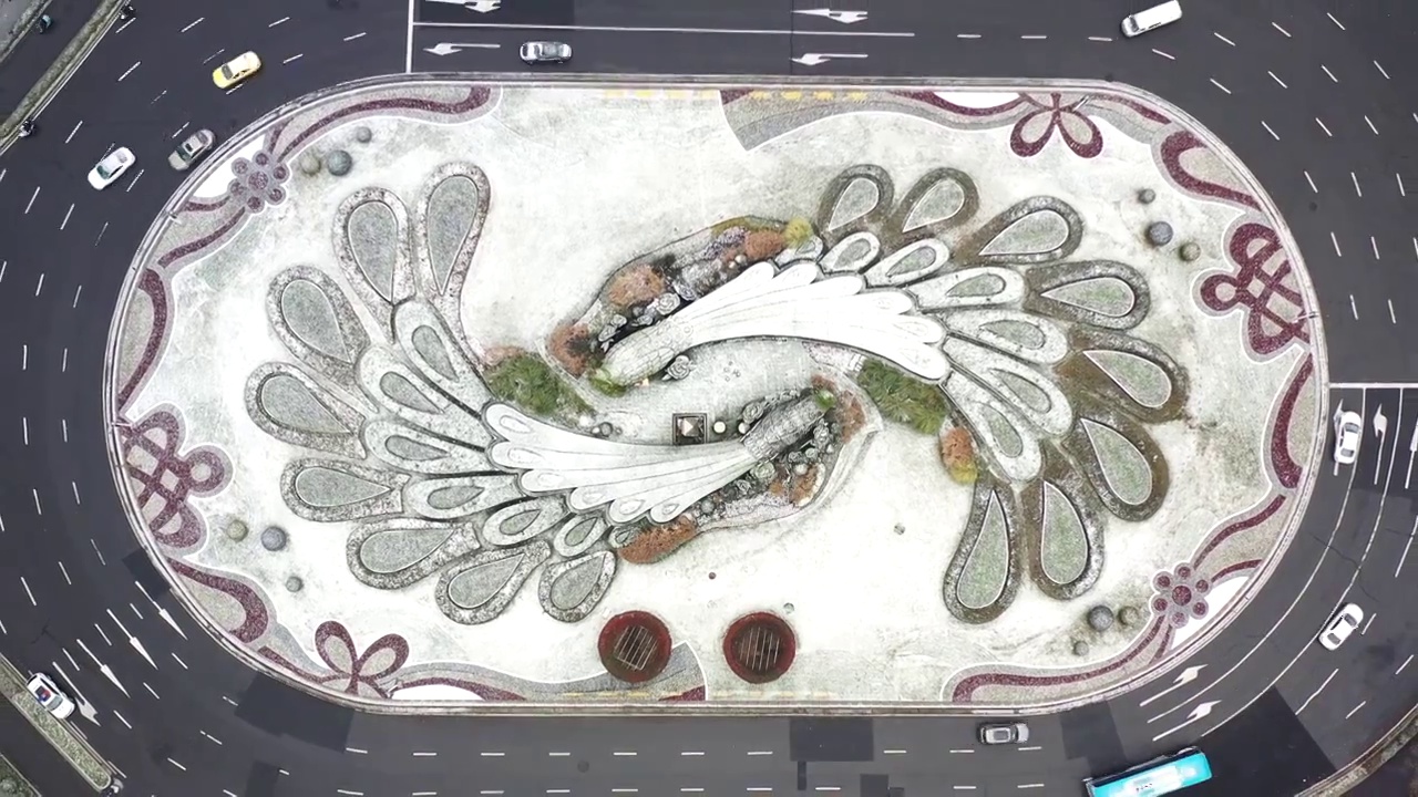 航拍上升视角鸟瞰雪中南京鼓楼广场环岛的孔雀绿植雕塑视频下载