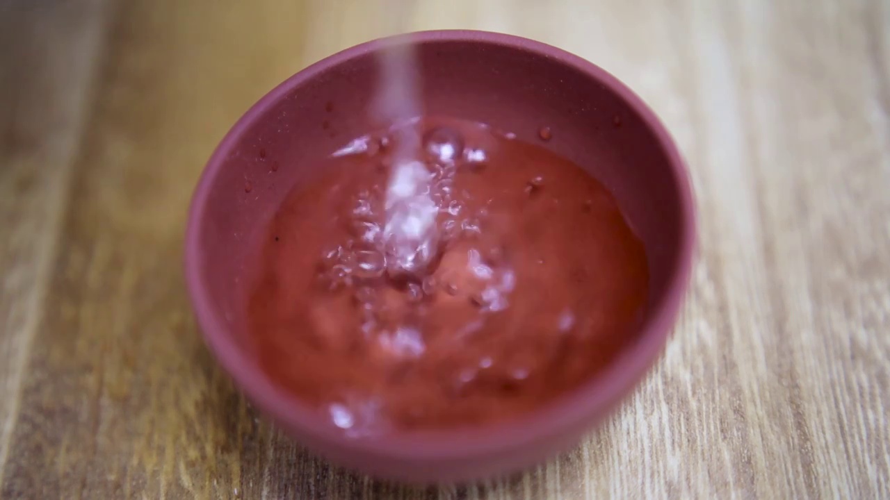 慢动作拍摄将茶壶中泡好的热茶水倒入木制桌面上的紫砂茶杯中视频素材