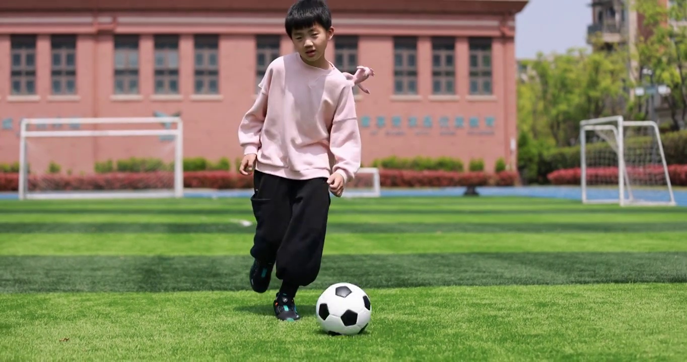 男孩在足球场上踢球的慢动作视频素材