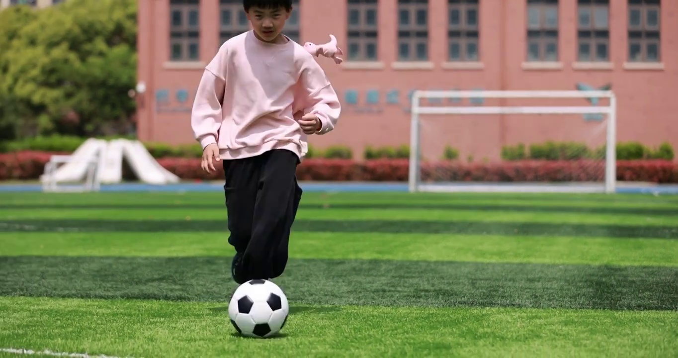男孩在足球场上踢球的慢动作视频素材
