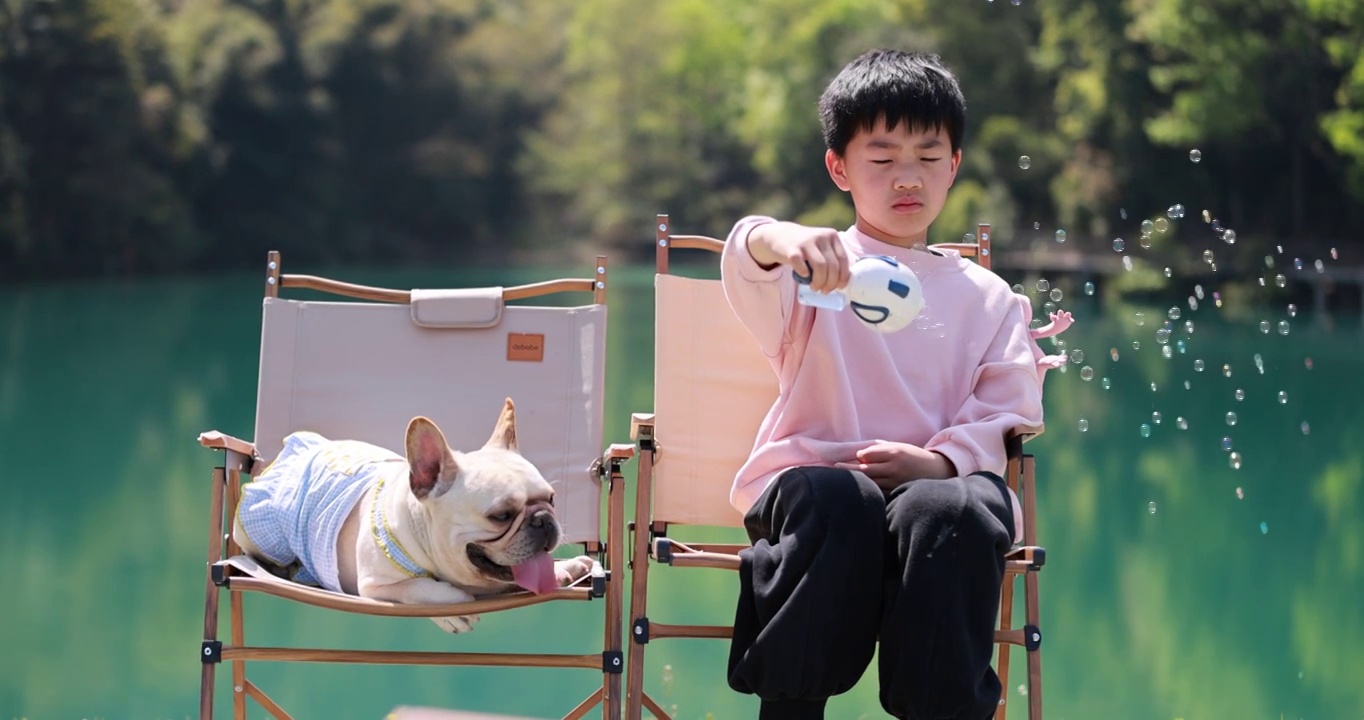 可爱的小男孩和他的狗在湖边玩耍慢镜头视频素材
