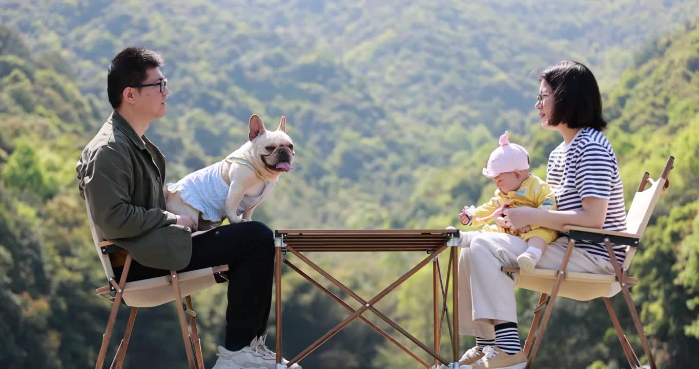 一家三口和宠物狗在户外露营交谈的慢镜头视频素材