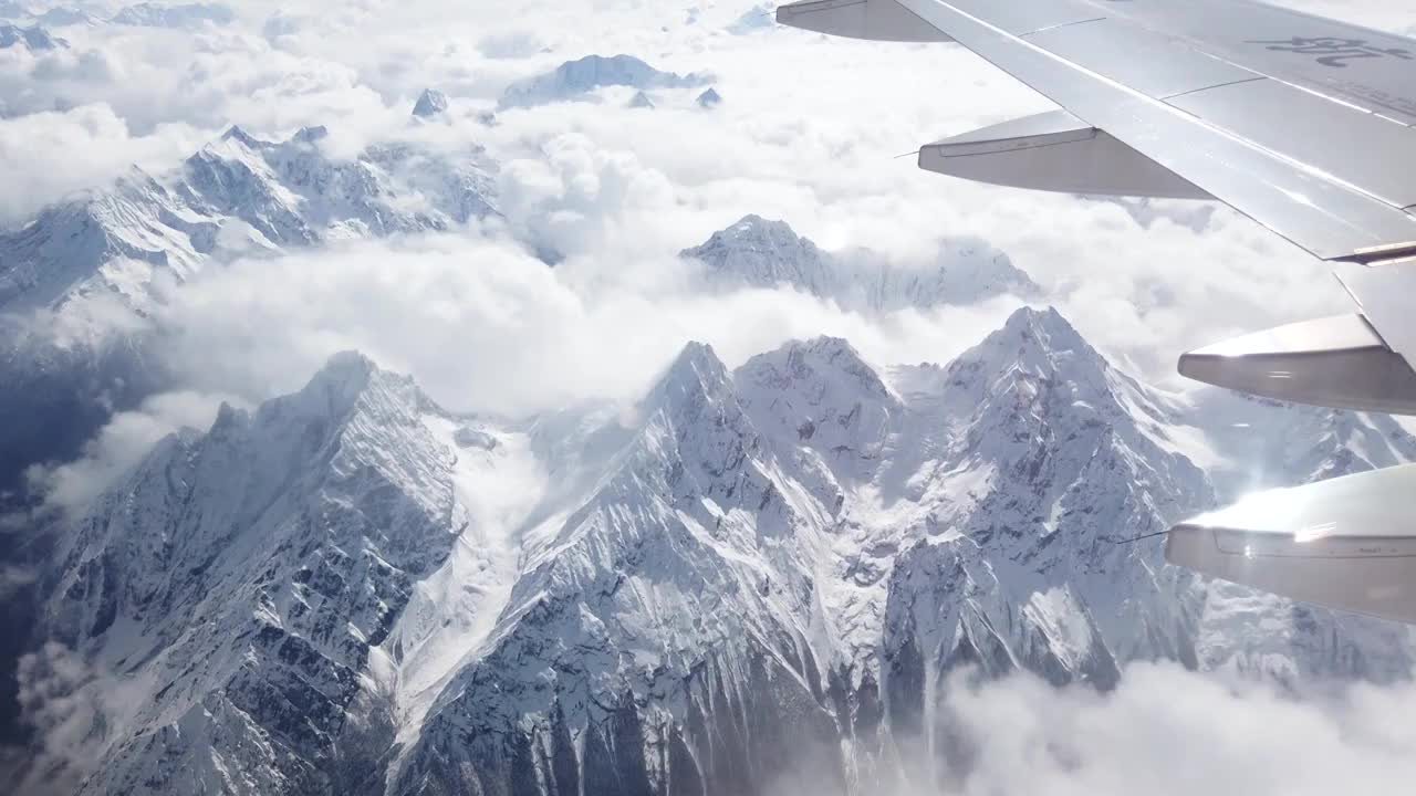 透过飞机舷窗往外看，飞机飞行在雪山和云海上视频下载