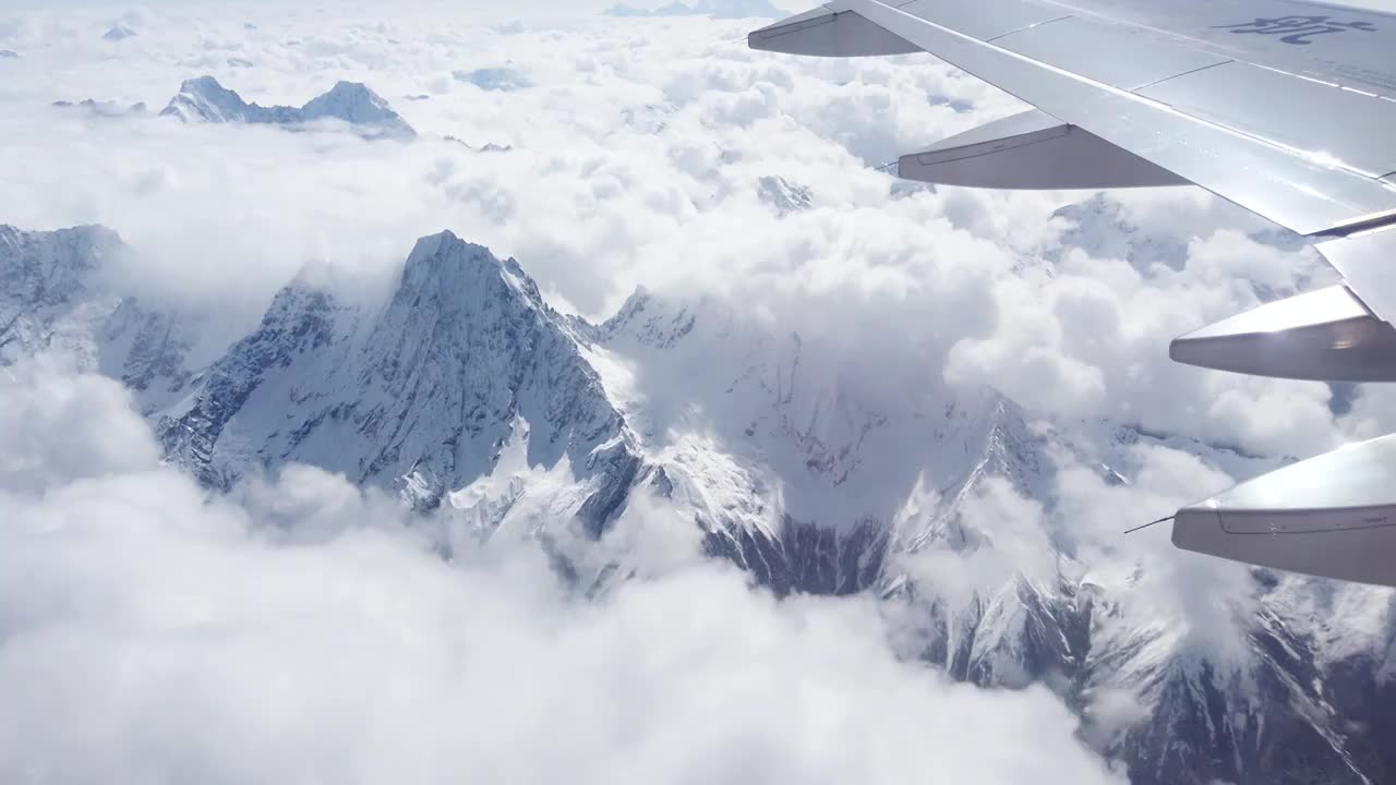 透过飞机舷窗往外看，飞机飞行在雪山和云海上视频素材