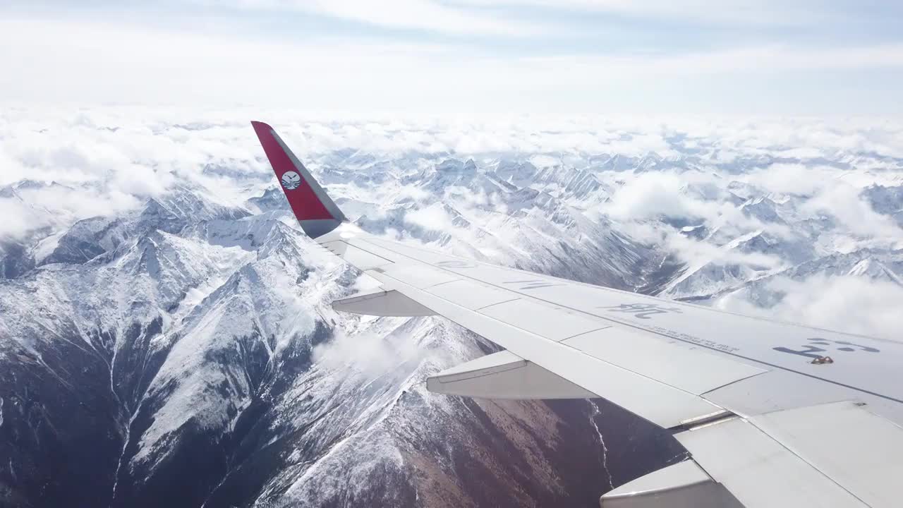 透过飞机舷窗往外看，飞机飞行在雪山和云海上视频素材