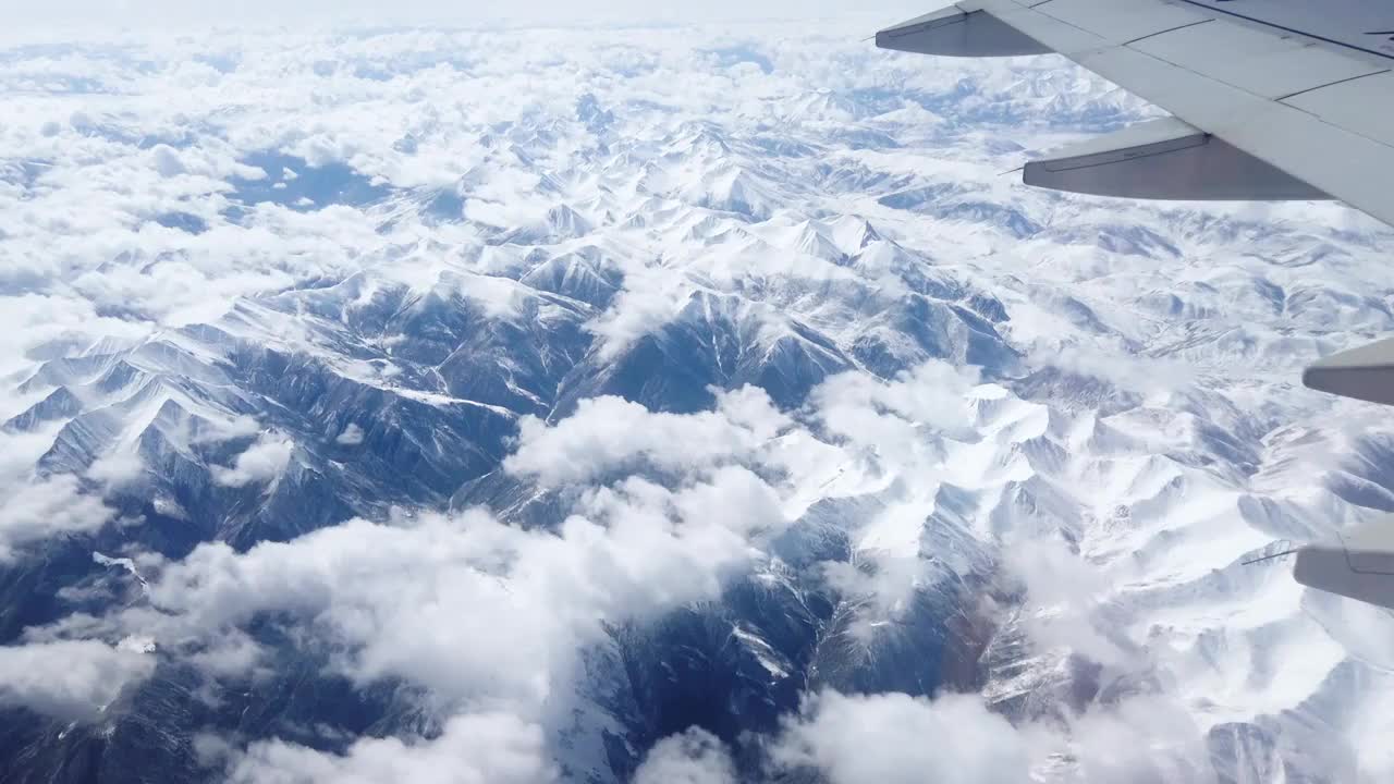 从飞机舷窗往外看，飞机飞行在雪山和云海上视频素材