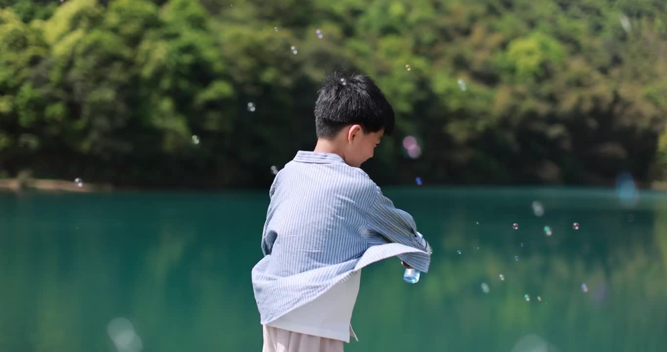 中国小男孩春日踏青，在湖边快乐地玩泡泡机唯美升格视频素材