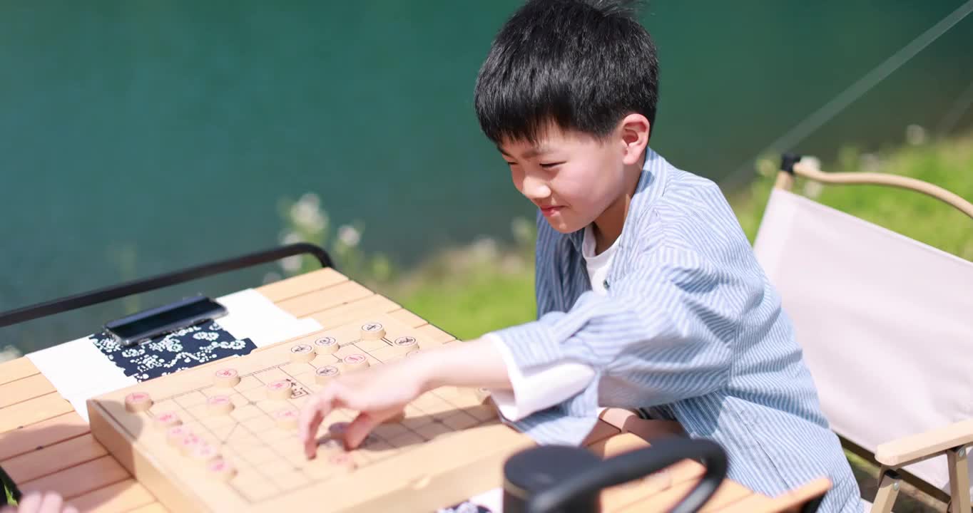 正在湖边下棋的中国小男孩视频素材