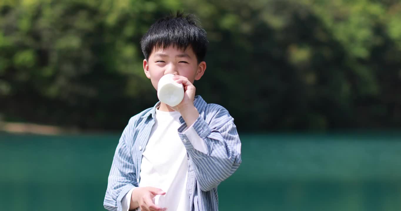 中国小男孩在户外喝有机牛奶视频素材