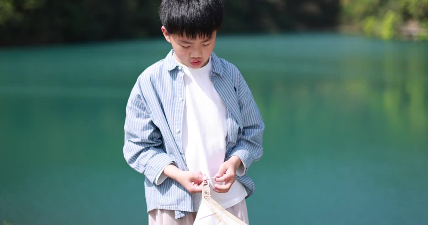 中国小男孩正在湖边扎帐篷视频素材