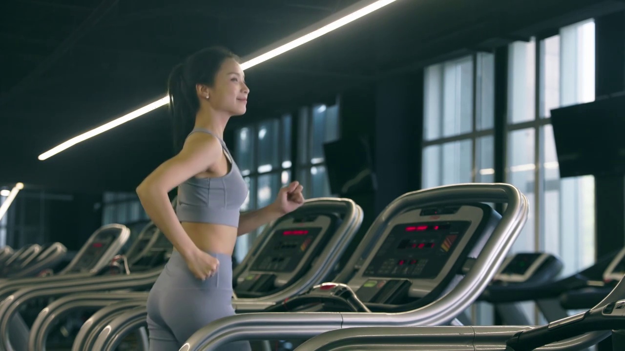 在健身房使用跑步机的年轻女性视频下载