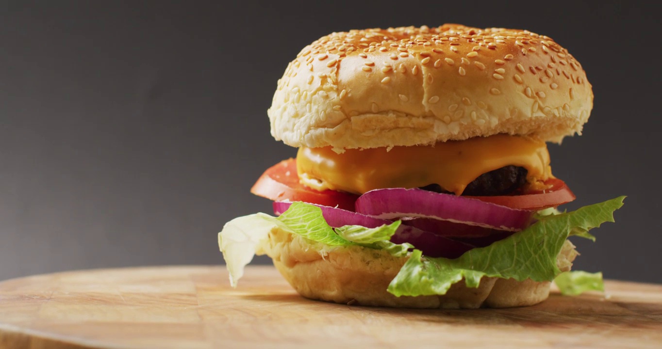 视频芝士汉堡与沙拉在汉堡面包，在灰色背景与复制空间视频下载