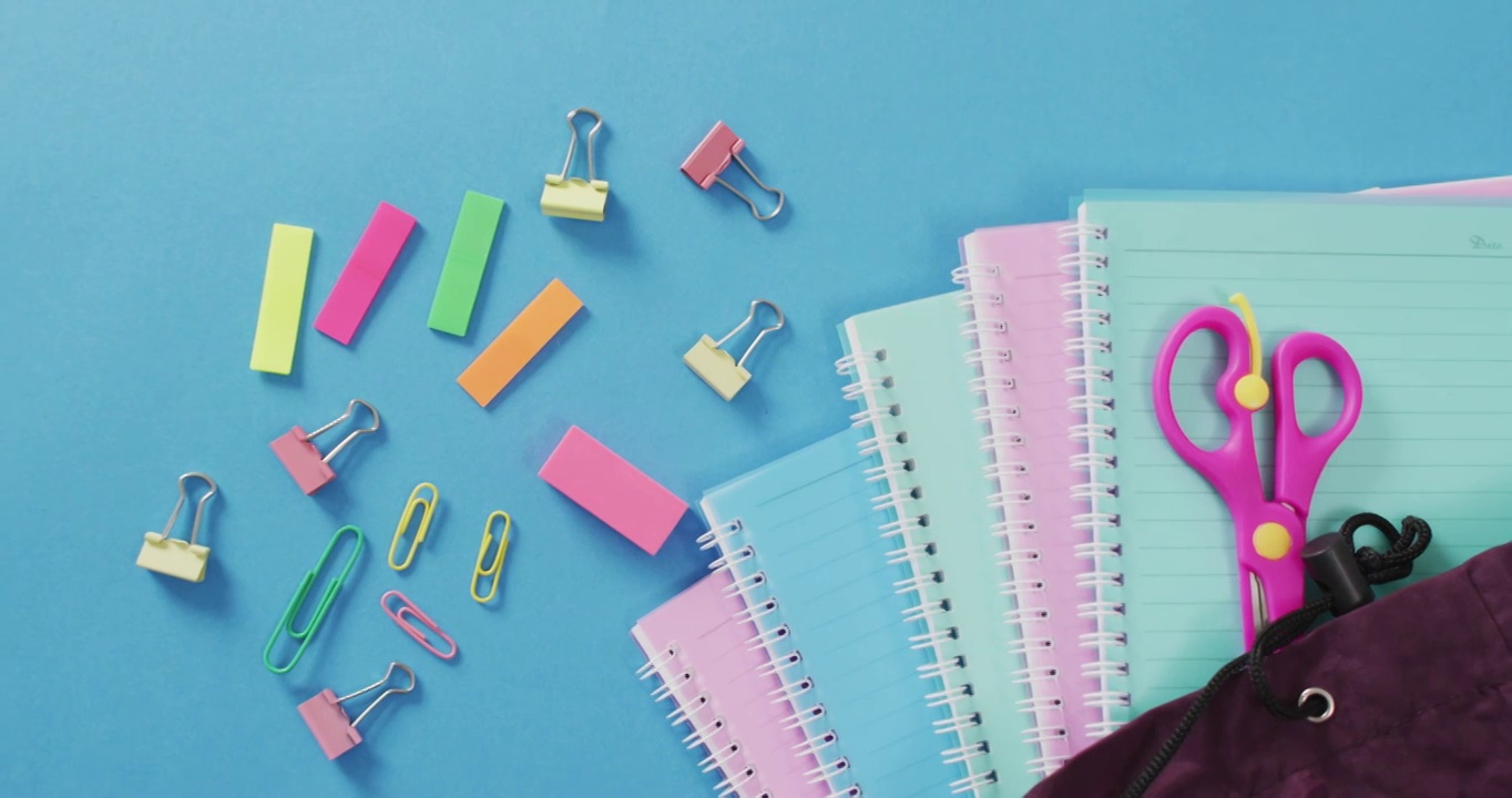 视频的学校用品，笔记本，笔，记号笔和笔记本在蓝色背景视频下载