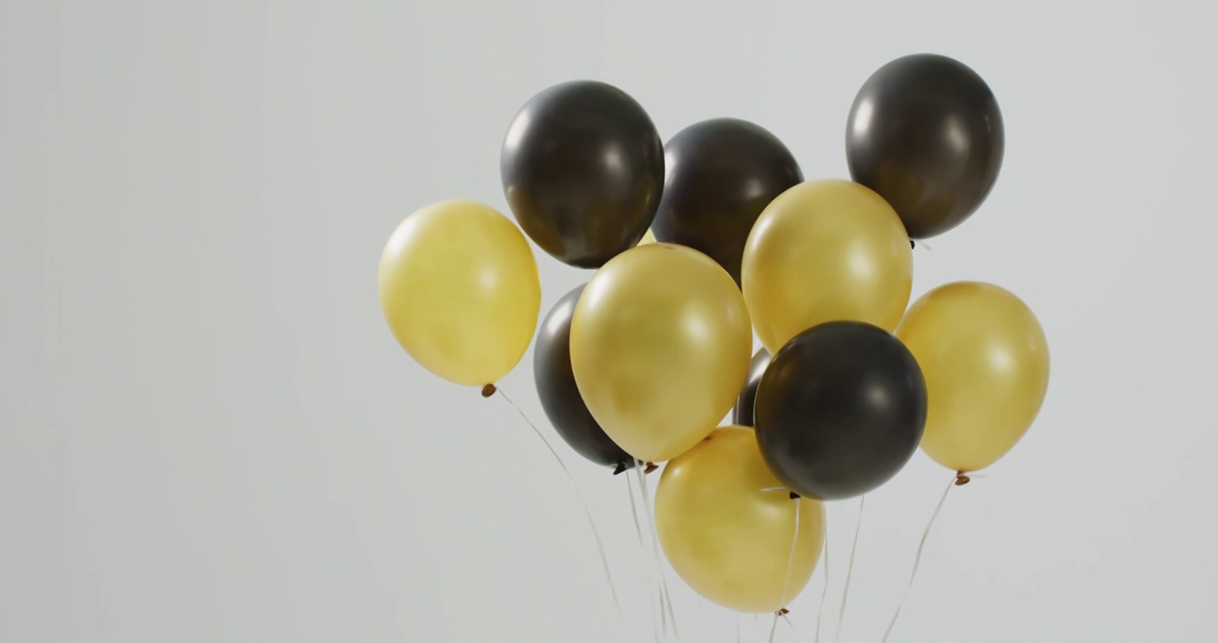 黑色和金色气球漂浮在白色背景的视频，带有复制空间视频下载