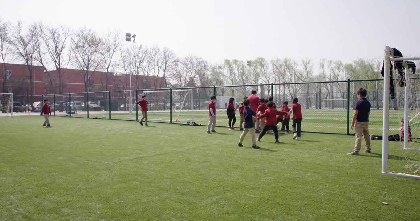 国际学校学生在绿茵场上踢足球视频下载