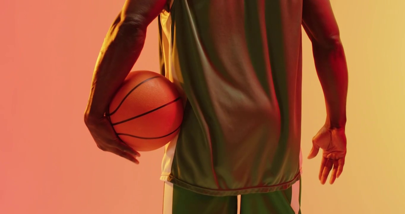视频后视图的非裔美国男子篮球运动员拿着球在橙色背景视频下载