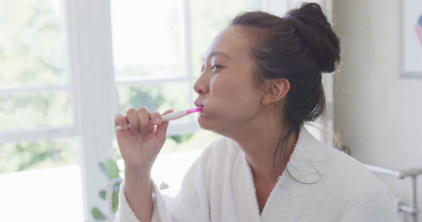 快乐的亚洲女人在浴室刷牙，慢镜头视频下载